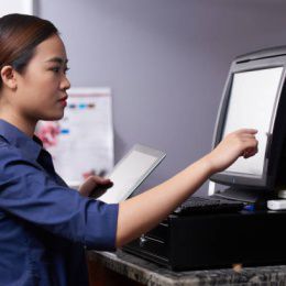 Pretty young waitress entering order details in computer